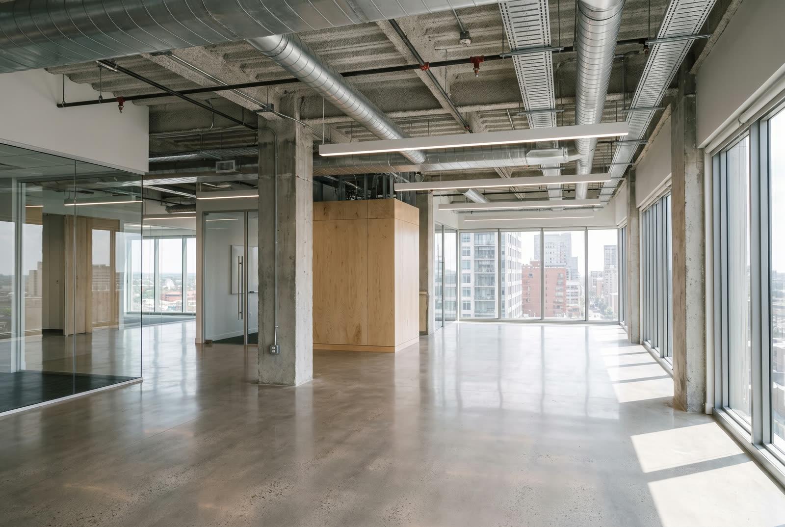 Newly completed modern commercial office build-out with exposed industrial-chic ceiling and large windows, pristine and unoccupied